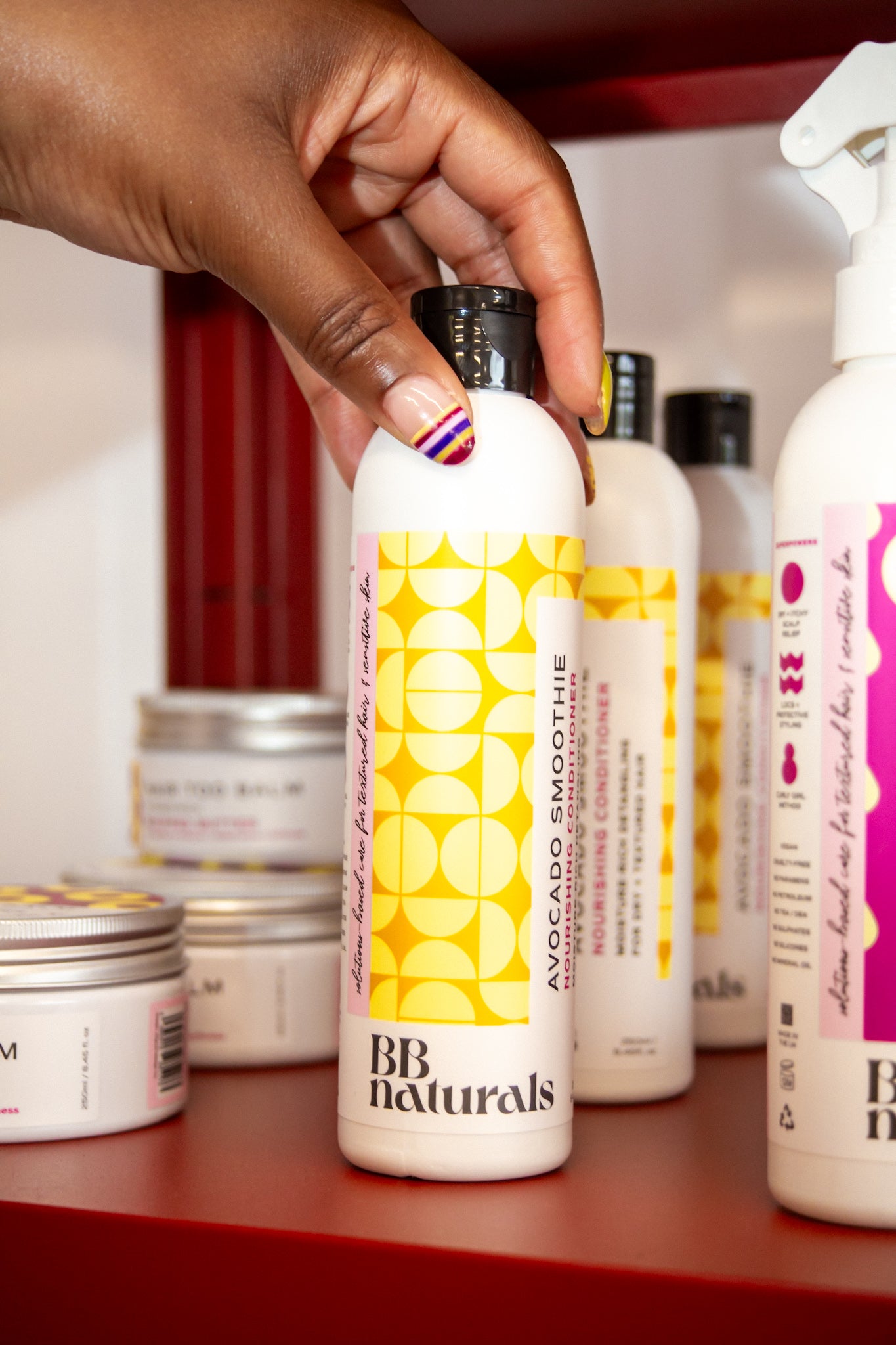 Hand holding a BB Naturals product on a shelf with other skincare items.