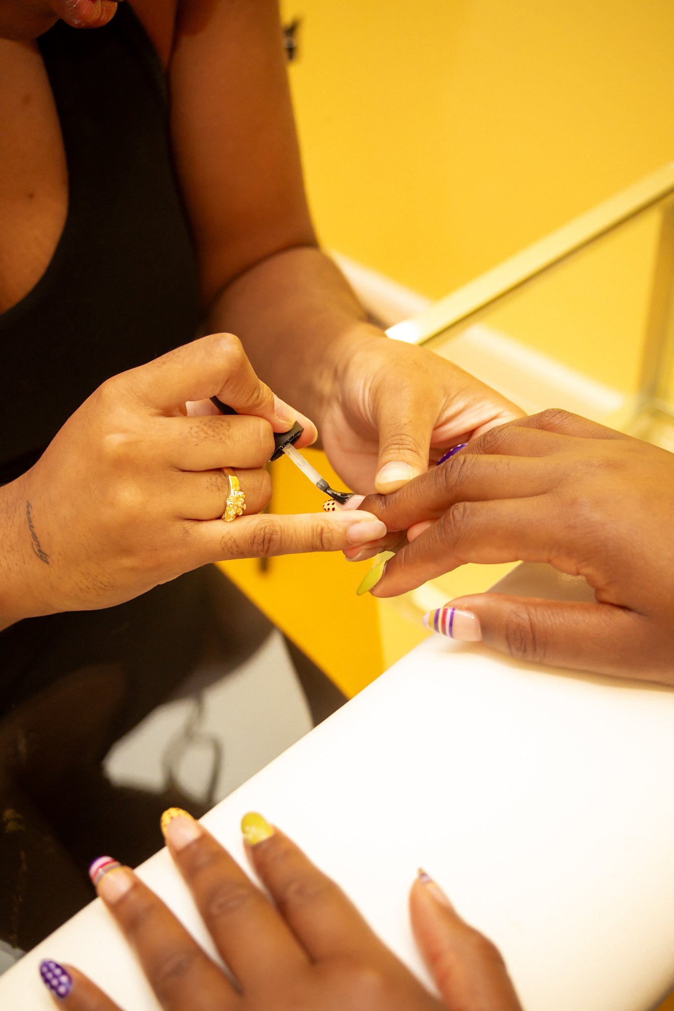 Black women getting her nails painted by a Black nail tech