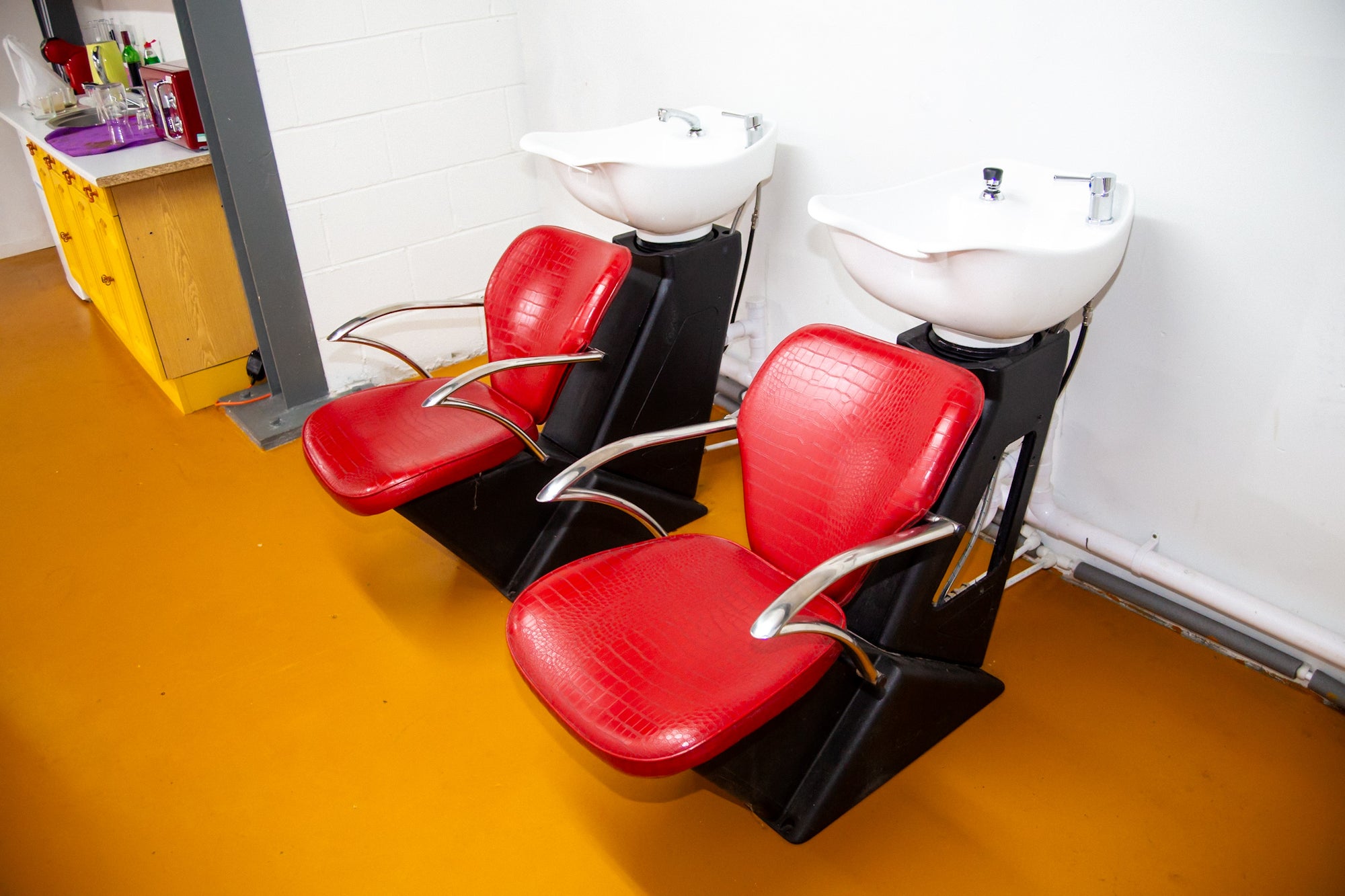 Red hair washing chairs with white sinks in a salon setting.